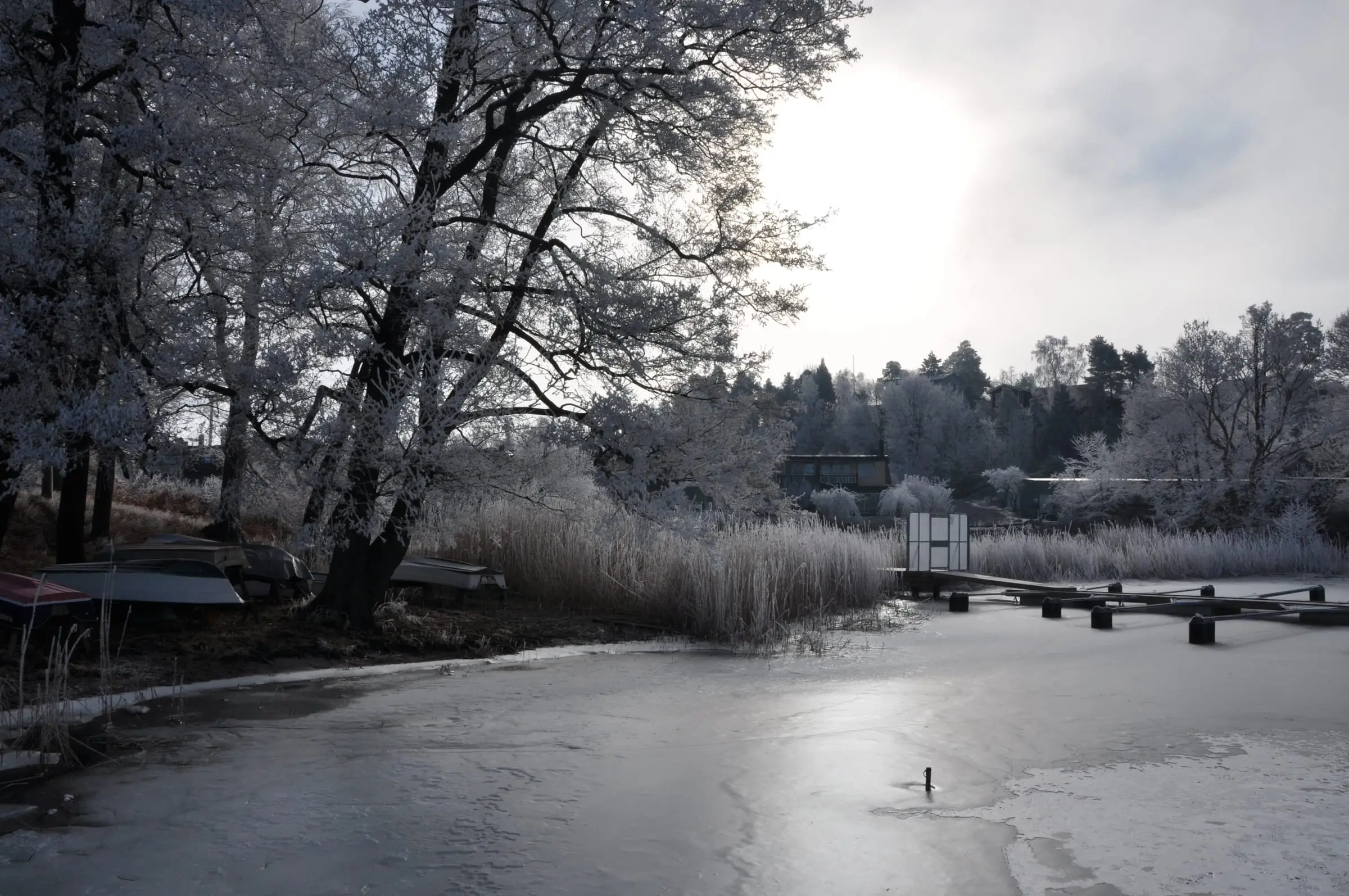 Blynäsviken en frostmorgon, med upplagda småbåtar och bryggor infrusna i isen.