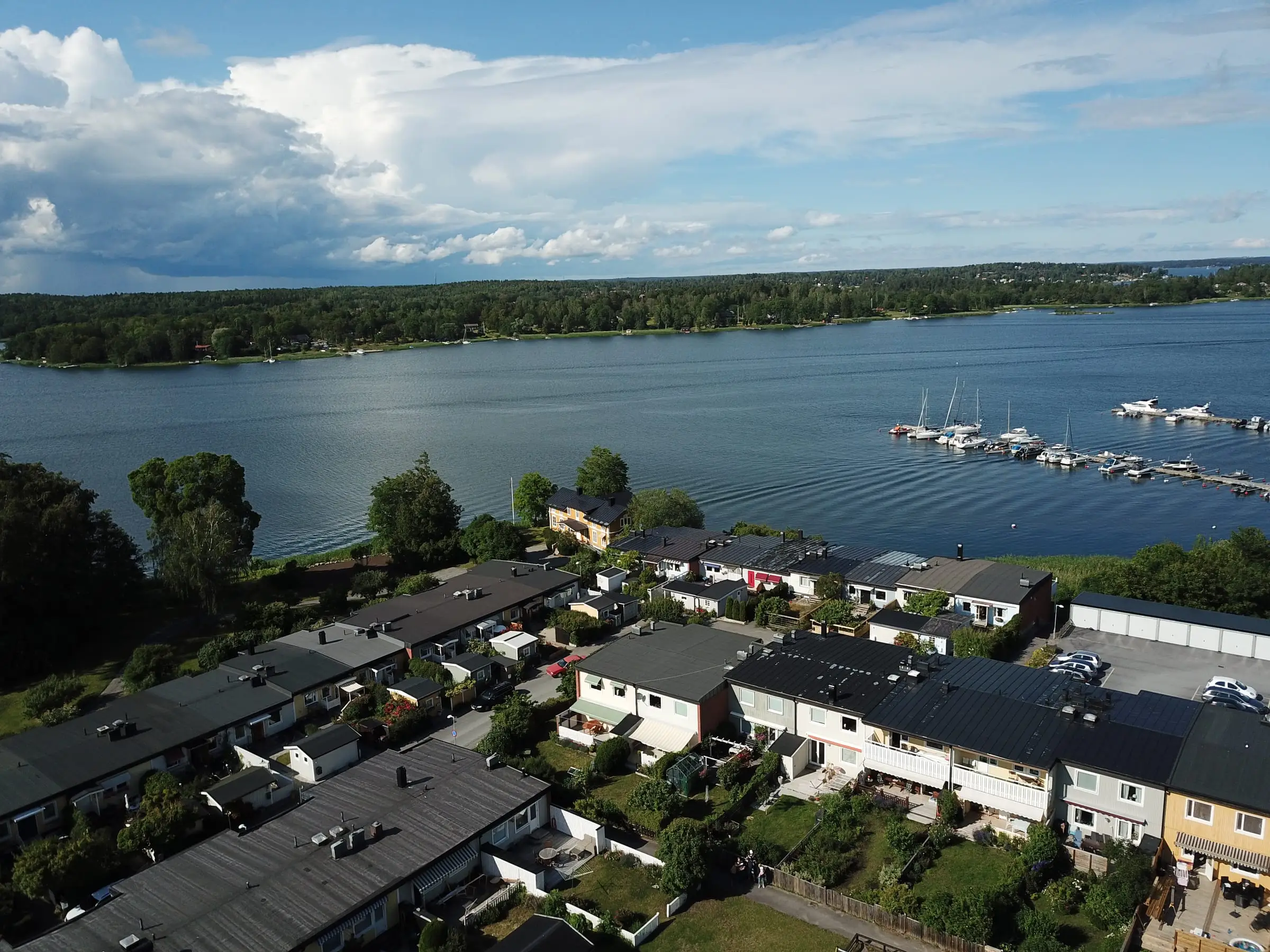 Blynäs radhuslängor sedda från luften, med Blynäsviken, marinans bryggor och Vaxholmsfjärden bakom.