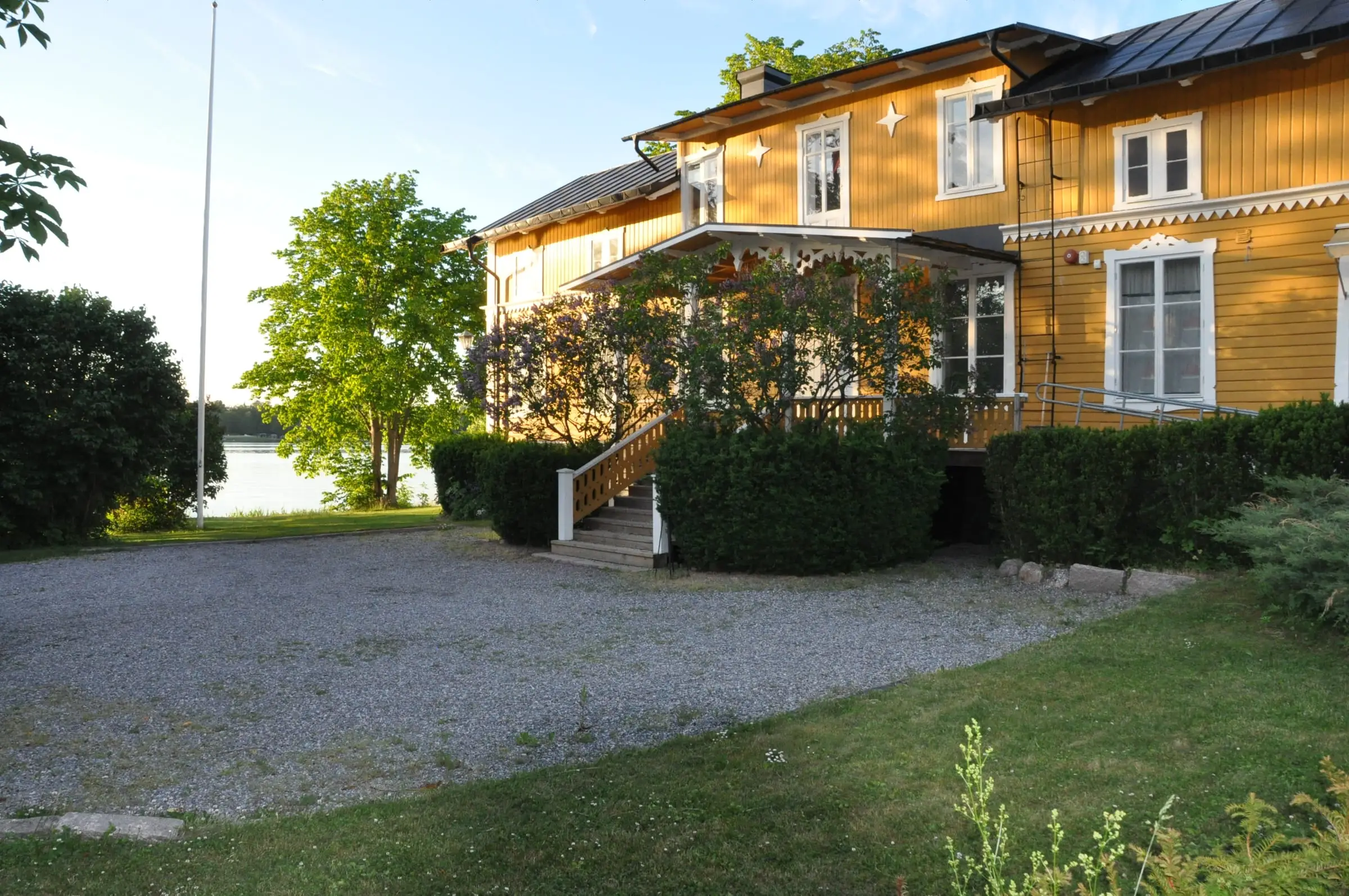 Blynäsgården, en gul träbyggnad med veranda och vita knutar.